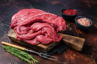 Tahta kesme tahtasına dilimlenmiş çiğ et filetosu. Karanlık arka plan. Üst görünüm