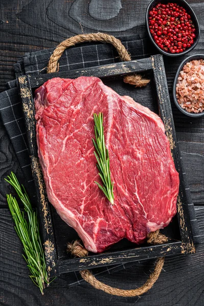 Filetto crudo di manzo per bistecche in un vassoio di legno con erbe. Fondo in legno nero. Vista dall'alto — Foto Stock