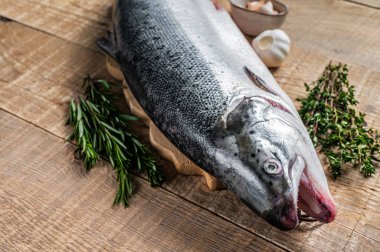 Tahta bir kichen masasında otlarla birlikte çiğ somon balığı. Ahşap arka plan. Üst görünüm