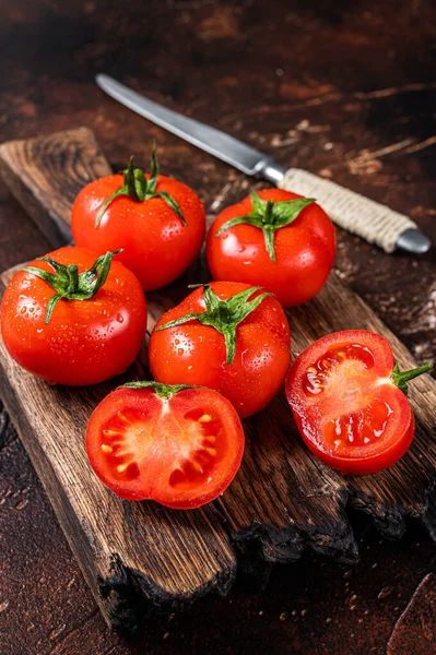 Rote Kirschtomaten auf einem Holzschneidebrett schneiden. Dunkler Hintergrund. Ansicht von oben — Stockfoto