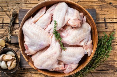 Tahta bir tabakta çiğ tavuk kanadı kekik ve sarımsaklı. Ahşap arka plan. Üst görünüm