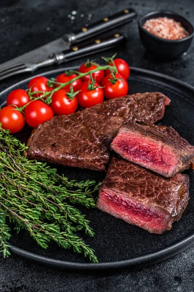 Pečený hovězí steak z denveru na talíři s tymiánem. Černé pozadí. Horní pohled — Stock fotografie