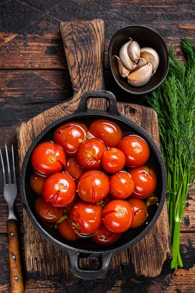 Gesalzene eingelegte Kirschtomaten in einer Pfanne mit Kräutern und Dill. Dunkler Holzhintergrund. Ansicht von oben — Stockfoto