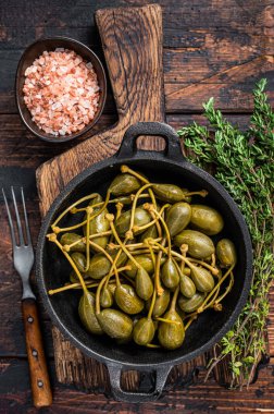 Tavada marine edilmiş konserve kapari. Koyu ahşap arka plan. Üst görünüm