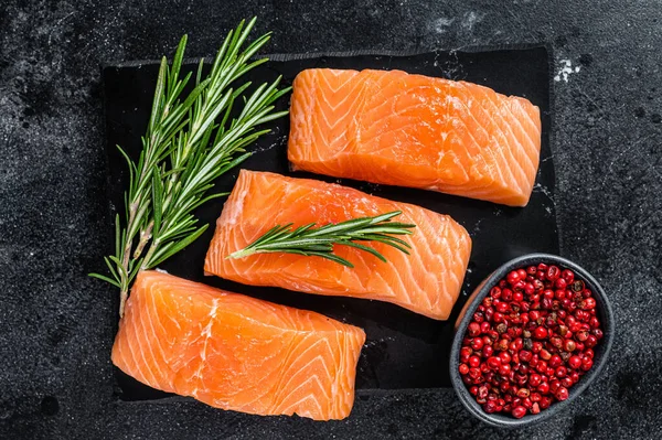 Rauwe zalmfilet steaks op marmeren bord met kruiden. Zwarte achtergrond. Bovenaanzicht — Stockfoto