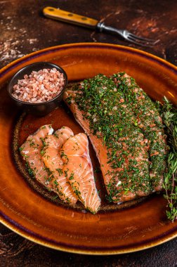 Somon Gravlax dereotlu ve pembe tuzlu kırsal tabakta. Karanlık arka plan. Üst görünüm