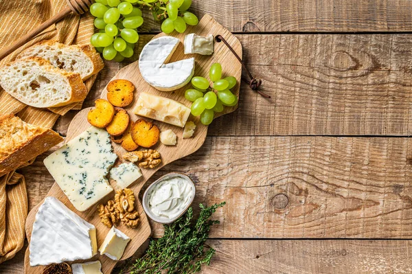 Cheese Board. Brie, Camembert, Roquefort, parmesan and blue cream cheese with grape, fig, bread and nuts on wooden board. wooden background. Top view. Copy space — Stock Photo, Image