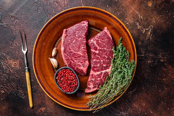 Carne fresca cruda denver o bistecca di carne a lama superiore su un piatto rustico con timo. Sfondo scuro. Vista dall'alto — Foto Stock