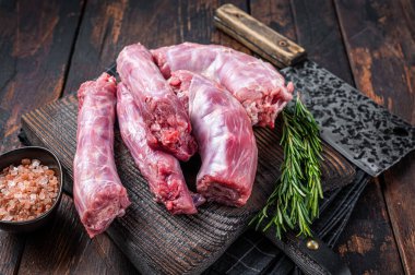 Uncooked Raw Turkey necks meat on a butcher wooden board with cleaver. Dark wooden background. Top View clipart