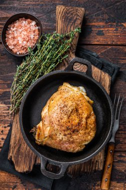 Biberiye ve tuzlu tavada pişmiş tavuk budu. Koyu ahşap arka plan. Üst Görünüm