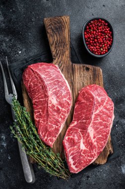 Taze Raw Top Blade ya da kasap kesim tahtasındaki düz demir et biftekleri. Siyah arka plan. Üst Görünüm