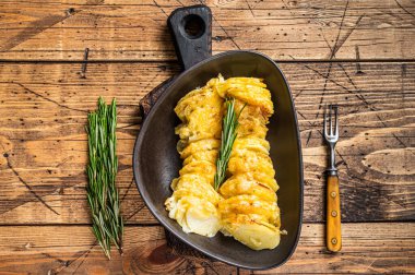 Bitkilerle dolu bir tabakta patates güveci. Ahşap arka plan. Üst Görünüm