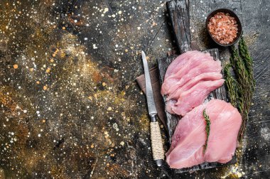 Kasap bıçağıyla dilimlenmiş çiğ hindi göğsü fileto eti. Kahverengi arka plan. Üst Manzara. Boşluğu kopyala