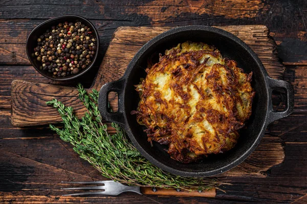 Kızarmış patates gözlemesi ya da tavada otlu börek. Koyu ahşap arka plan. Üst görünüm