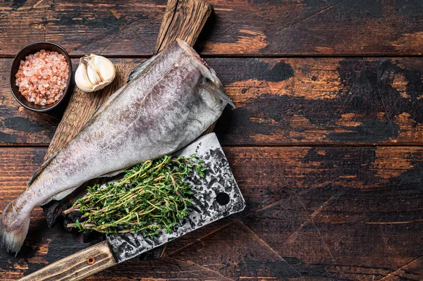新鲜的生鳕鱼或鳕鱼用刀叉在木板上。深色的木制背景。顶部视图。复制空间 — 图库照片