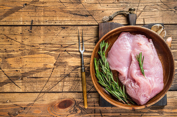 Сырое филе индейки, мясо птицы в деревянной тарелке. деревянный фон. Вид сверху. Копирование пространства