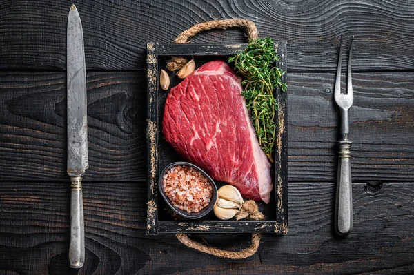 Syrový vrchní roštěnec hovězí steak z hovězí svíčkové nebo Picanha v dřevěném podnosu s bylinkami. Černé dřevěné pozadí. Horní pohled — Stock fotografie