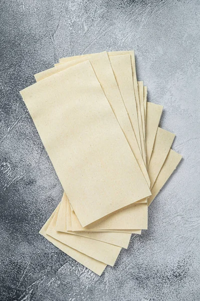 Rohe Lasagneblätter stapeln sich auf einem Küchentisch. Weißer Hintergrund. Ansicht von oben — Stockfoto
