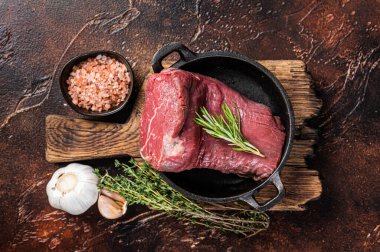 Tavada çiğ sığır fileto eti ve otlar. Karanlık arka plan. Üst görünüm