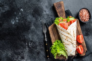 Salata ve sebzeli tortilla somonu rulosu. Siyah arka plan. Üst Manzara. Boşluğu kopyala