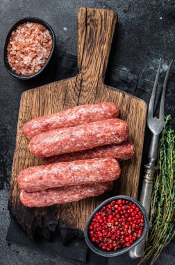 Ahşap bir tahtanın üzerinde pişmemiş çiğ et ve kuzu eti kebabı sosisi. Siyah arka plan. Üst görünüm