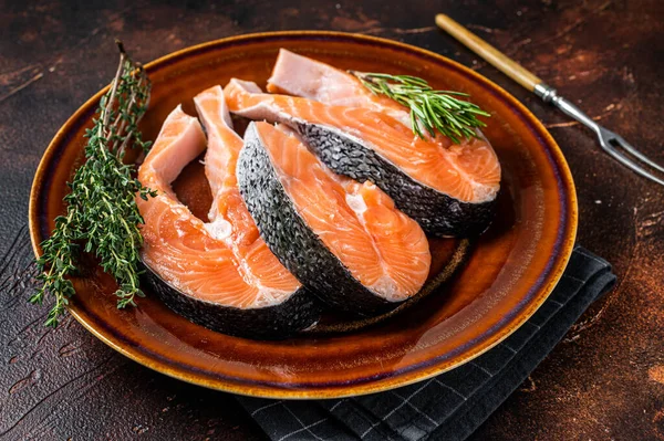 Bistecche crude di salmone su piatto rustico con erbe. Sfondo scuro. Vista dall'alto — Foto Stock
