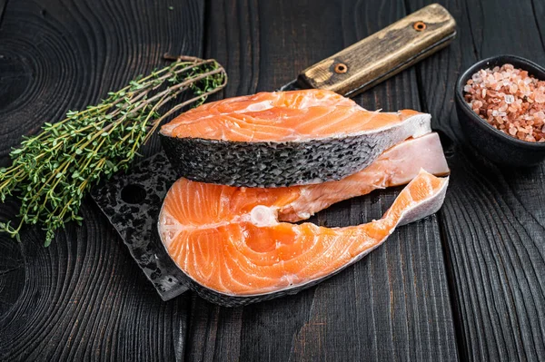 Bistecche fresche di salmone crudo sulla mannaia del macellaio. Fondo in legno nero. Vista dall'alto — Foto Stock