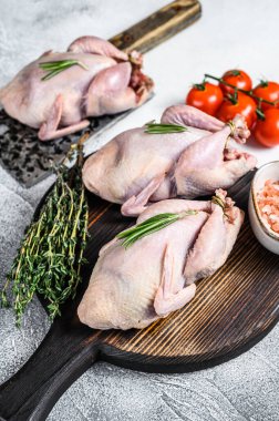 Çiğ bıldırcın hazırlama tahtasında et satırıyla. Beyaz arka plan. Üst görünüm