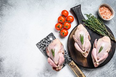 Çiğ bıldırcın hazırlama tahtasında et satırıyla. Beyaz arka plan. Üst Manzara. Boşluğu kopyala