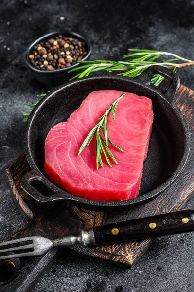Surowy stek z tuńczyka z rozmarynem na patelni. Czarne tło. Widok z góry — Zdjęcie stockowe