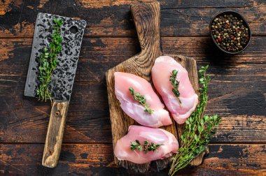 Tahta kesme tahtasının üzerinde çiğ tavuk derisiz fileto. Siyah arka plan. Üst görünüm