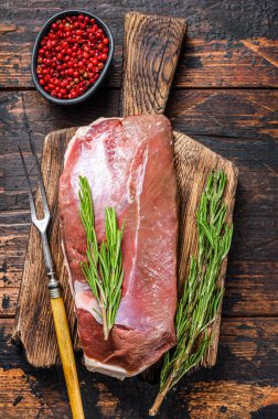 Çiğ ördek eti, göğüs bifteği, şifalı ve biberiyeli. Koyu ahşap arka plan. Üst görünüm