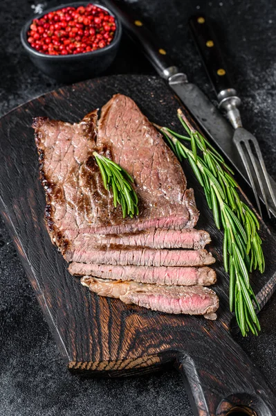 Grilovaný telecí steak na řezacím prkně. Černé pozadí. Horní pohled — Stock fotografie