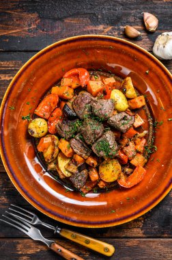 Sığır eti, patates, havuç ve ottan yapılmış İrlanda güveci. Koyu ahşap arka plan. Üst görünüm