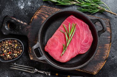 Tavada biberiyeli çiğ ton balığı filetosu. Siyah arka plan. Üst görünüm