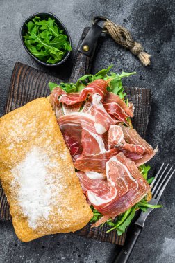 Ciabatta ekmeğinde Iberico Jamon jambonlu sandviç. Siyah arka plan. Üst görünüm
