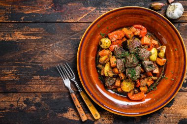 Sığır eti, patates, havuç ve ottan yapılmış İrlanda güveci. Koyu ahşap arka plan. Üst Manzara. Boşluğu kopyala