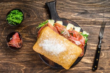 Jamon jambonlu sandviç, yanında roka ve peynirli peynirli ciabatta ekmeği. Ahşap arka plan. Üst görünüm