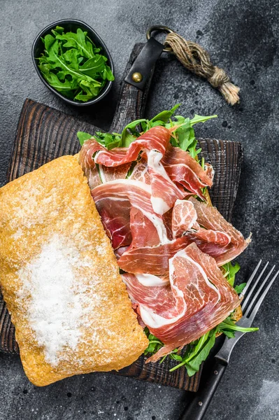 Panino al prosciutto iberico jamon sul pane ciabatta. Fondo nero. Vista dall'alto — Foto Stock