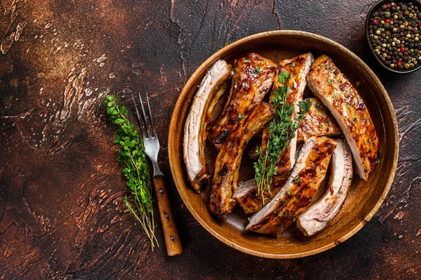 Cut BBQ grilled pork rack spareribs in a wooden plate. Dark background. Top view. Copy space — Stock Photo, Image