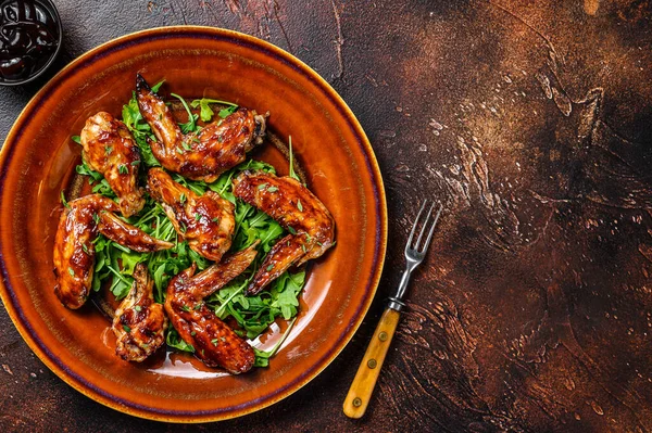 Asas de frango de búfalo Bbq em uma chapa com arugula. Fundo escuro. Vista superior. Espaço de cópia — Fotografia de Stock