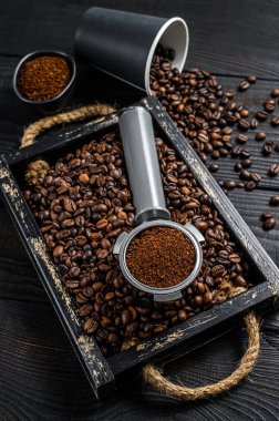 Espresso için Portafilter 'daki Ground Coffee kahve çekirdekli ahşap bir tepside. Siyah ahşap arka plan. Üst görünüm