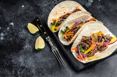 Biftek, soğan, domates ve tatlı biberli Meksika taco kabuğu. Siyah arka plan. Üst Manzara. Boşluğu kopyala