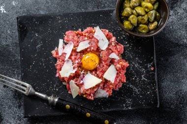 Bıldırcın yumurtası, kapari ve parmesan peynirli Tatar bifteği. Siyah arka plan. Üst görünüm