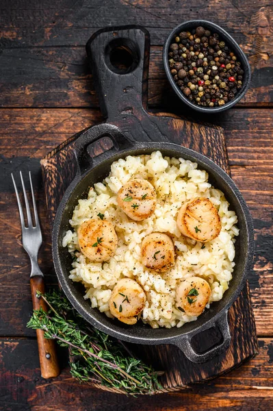 Risotto aux fruits de mer avec pétoncles dans une casserole. Fond en bois foncé. Vue du dessus — Photo