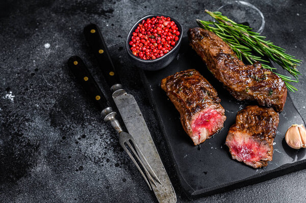 Grilled brisket steaks in bbq sauce on a marble board. Black background. Top view. Copy space