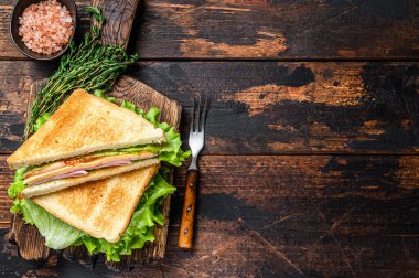 Peynirli, domatesli ve marullu Hindi jambonlu sandviç. Koyu ahşap arka plan. Üst Manzara. Boşluğu kopyala