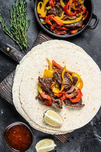 Mexikói Fajitas színes borssal és hagymával, tortillával és salsával tálalva. Fekete háttér. Felülnézet — Stock Fotó