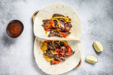 Et şeritli Fajitalar, renkli dolmalık biber ve soğan, tortilla ve salsa ile servis edilir. Beyaz arka plan. Üst görünüm