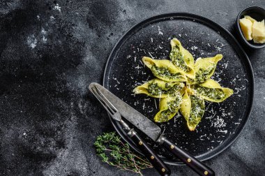 Biftek ve ıspanakla doldurulmuş İtalyan Jumbo kabuklu Conchiglioni makarnası. Siyah arka plan. Üst Manzara. Boşluğu kopyala